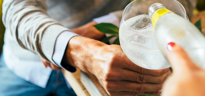 pouring gin into a glass at a distillery