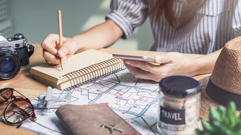 a young traveller plans out their trip to Pasadena with a notebook and map