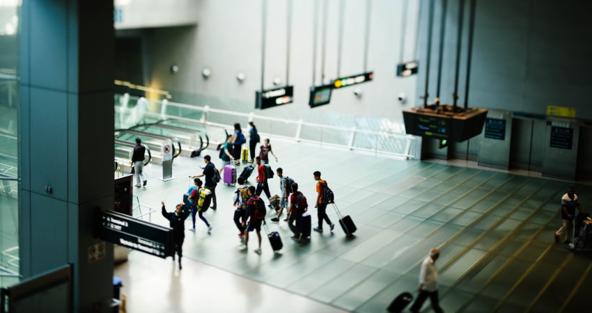 a large group of people with suitcases walk through an airport toward a gate