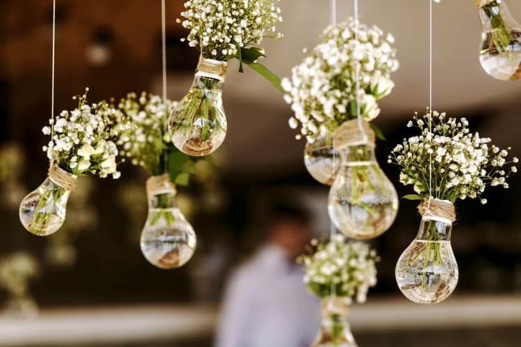 Light bulbs filled with flowers that are suspended from the ceiling