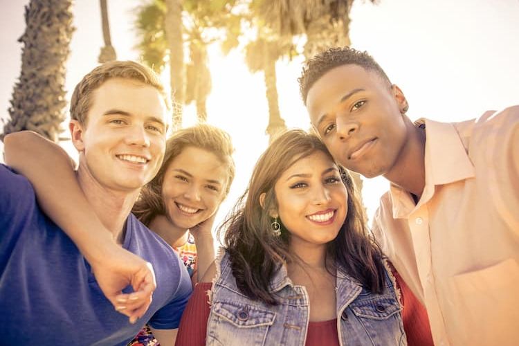 Four friends outside in LA near palm trees