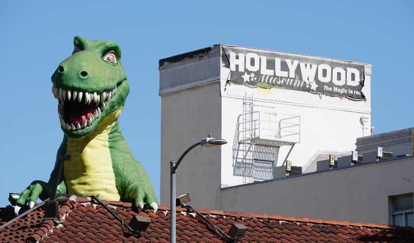 A big dinosaur statue peeks over a rooftop next to the Hollywood Museum in Los Angeles