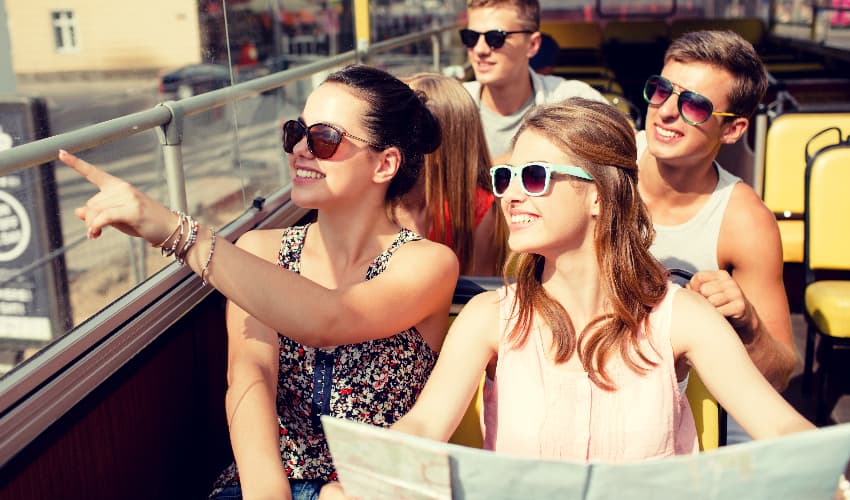A group of sightseers hold a map and point at attraction while riding on a private bus rental