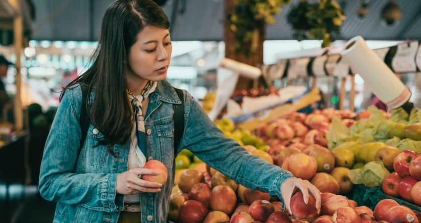 A woman picking out produce at a farmer's market