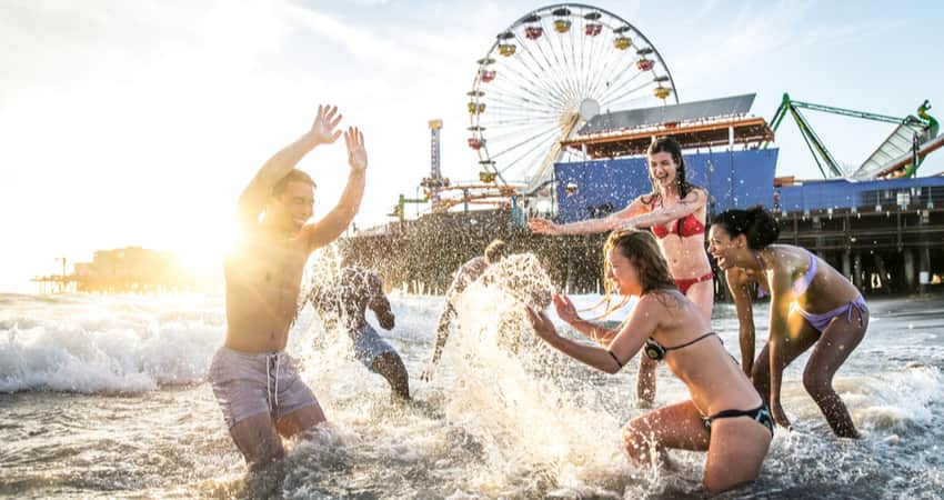 A group of friends playing in the water at Santa Monica Beach with the Pier in the background