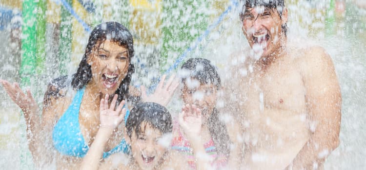 a family gets soaked in the middle of a water park fountain