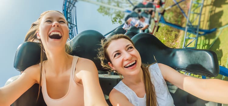 two riders in a rollercoaster car smile as the coaster swiftly rounds a turn