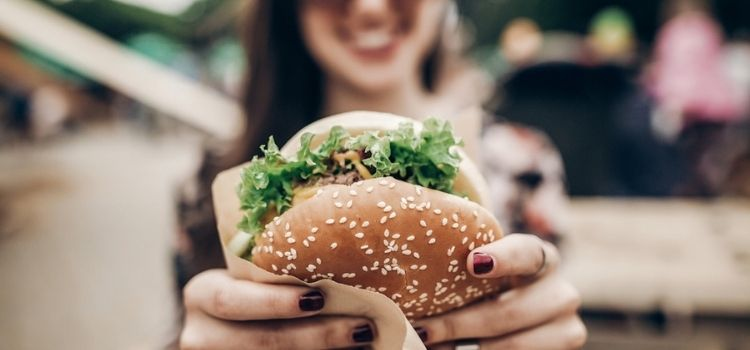 woman holding delicious burger at food festival