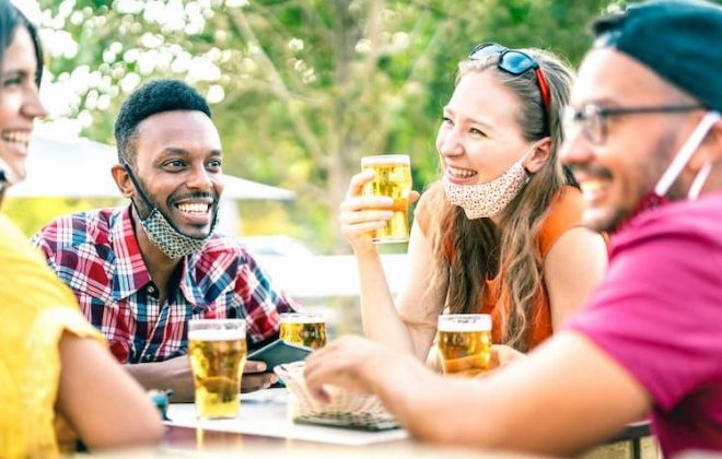 Friends drinking outside with face masks lowered