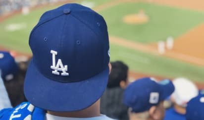 A close up of a fan wearing a Dodgers cap at a game