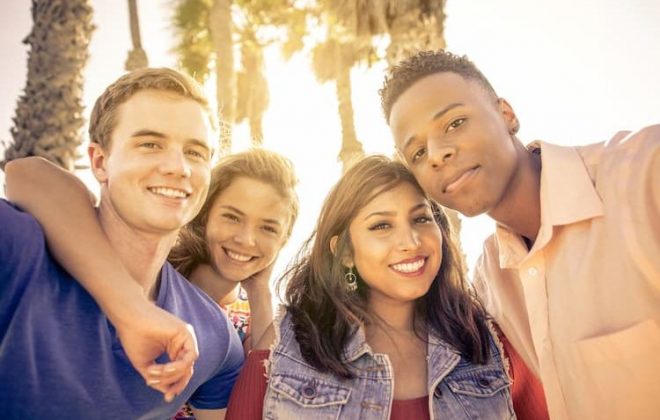Four friends outside in LA near palm trees
