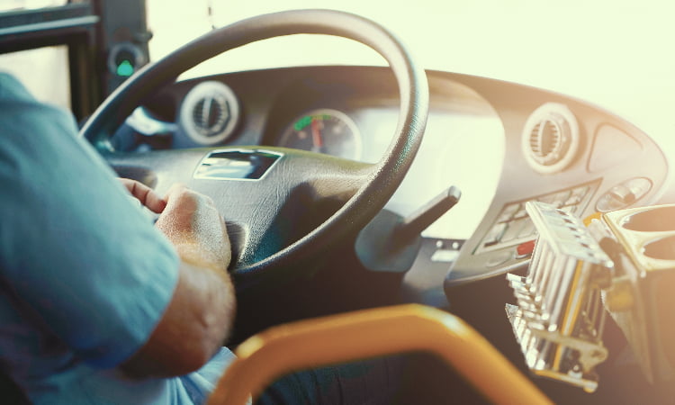 Over-the-shoulder view of a bus driver at the wheel of a bus