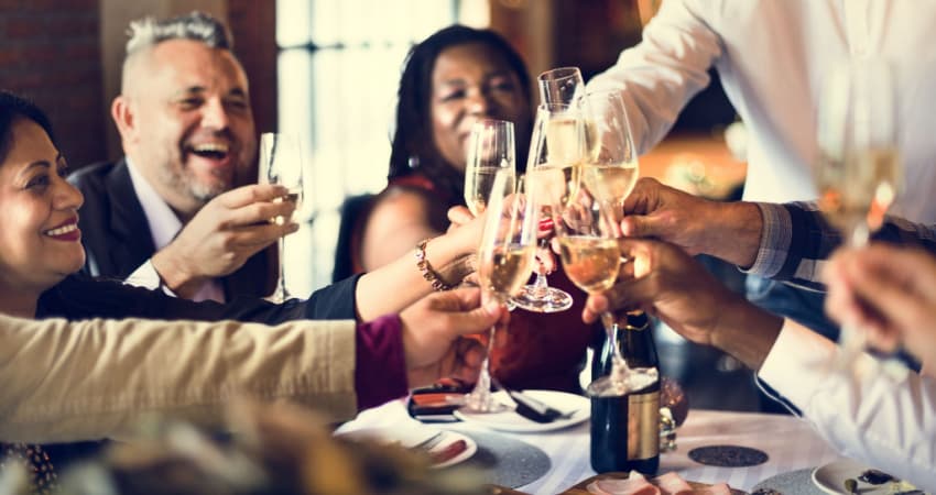 a group of people toasting champagne over dinner