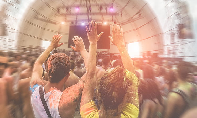 A large crowd jumps along to live music at an outdoor festival