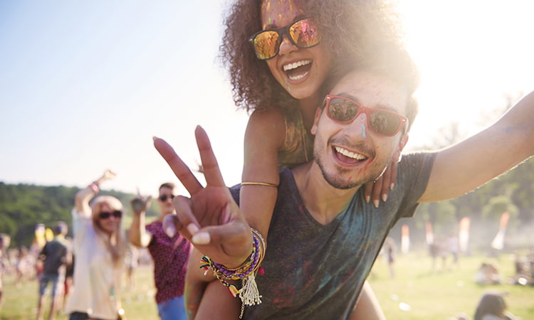 A woman rides piggyback on a friend, both smiling at a concert