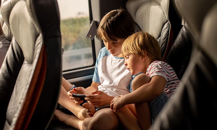 Two kids play a video game on a bus rental